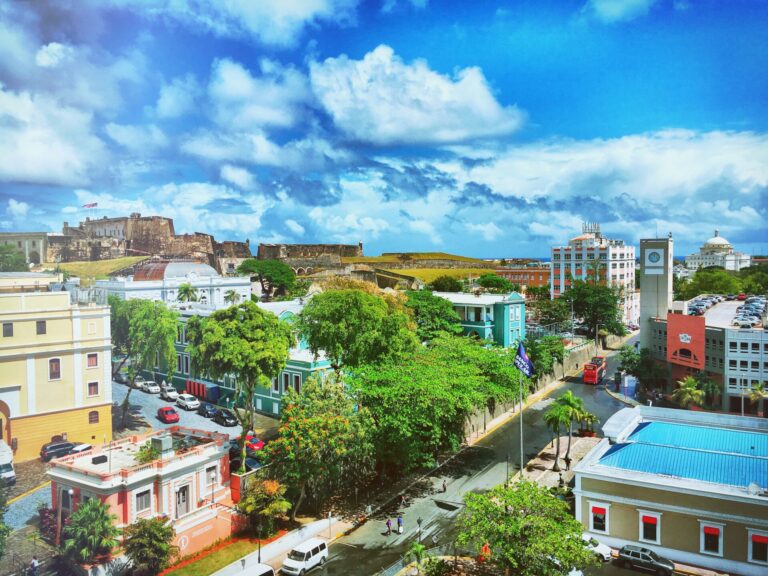 View of Old San Juan from the Doña Fela rooftop with Castillo San Cristóbal, colorful historic buildings, and El Capitolio de Puerto Rico.