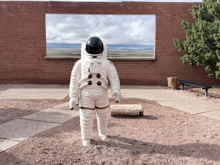 Astronaut training display at Meteor Crater in Arizona, featuring a suited astronaut figure beside rocky terrain and NASA-related exhibits.