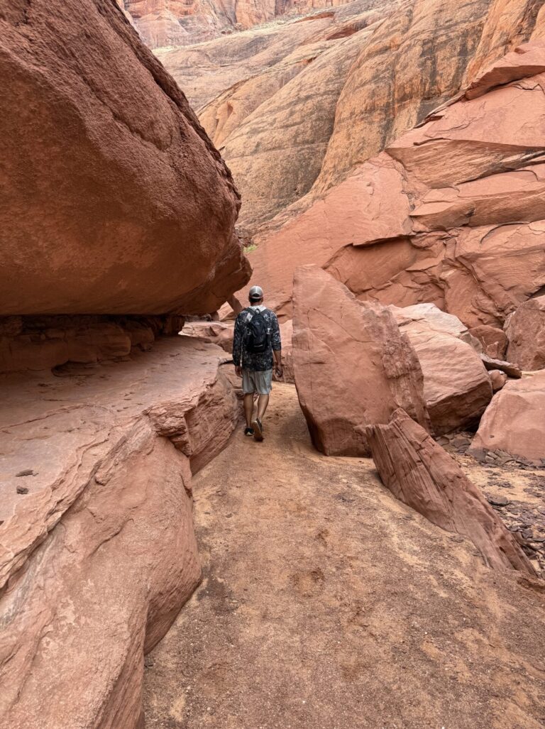 Walking through a narrow red sandstone canyon near the Colorado River in Glen Canyon, Arizona.