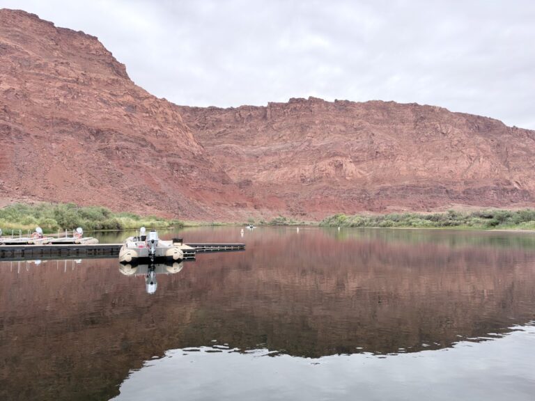 Backhaul boat on the calm Colorado River beneath red sandstone cliffs near Lees Ferry, Arizona.